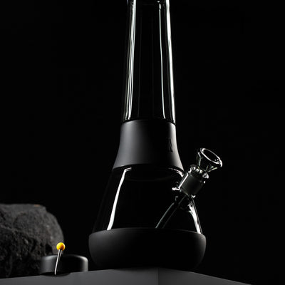 black modular bong with black glass. black background with stone. 