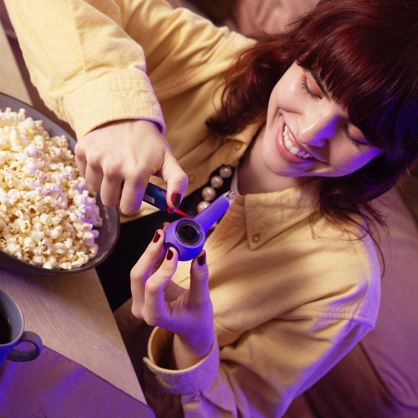 Woman using a grape purple pipe with popcorn.