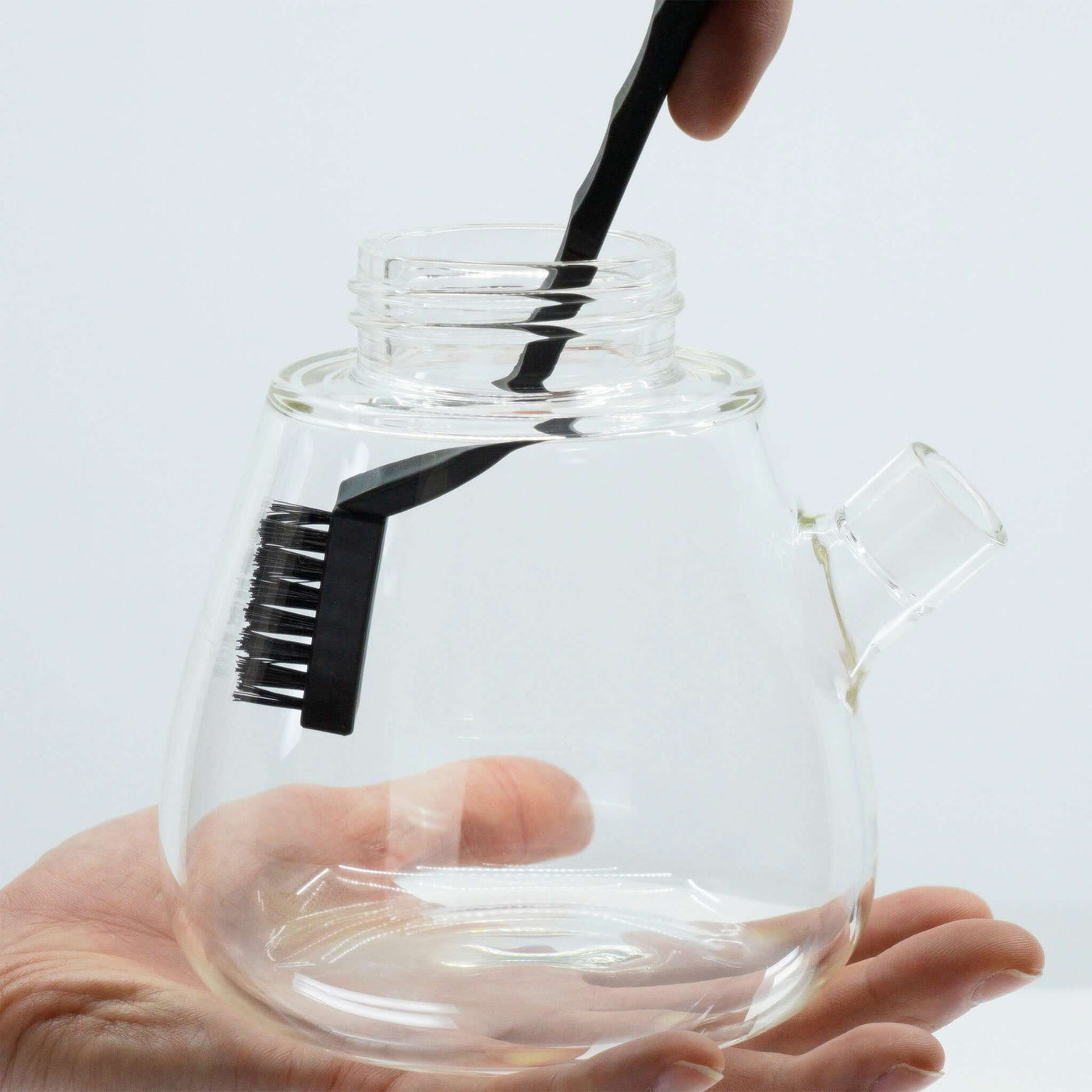 A person holding the bong base and using brush to clean the glass, showing the glass is easy to clean