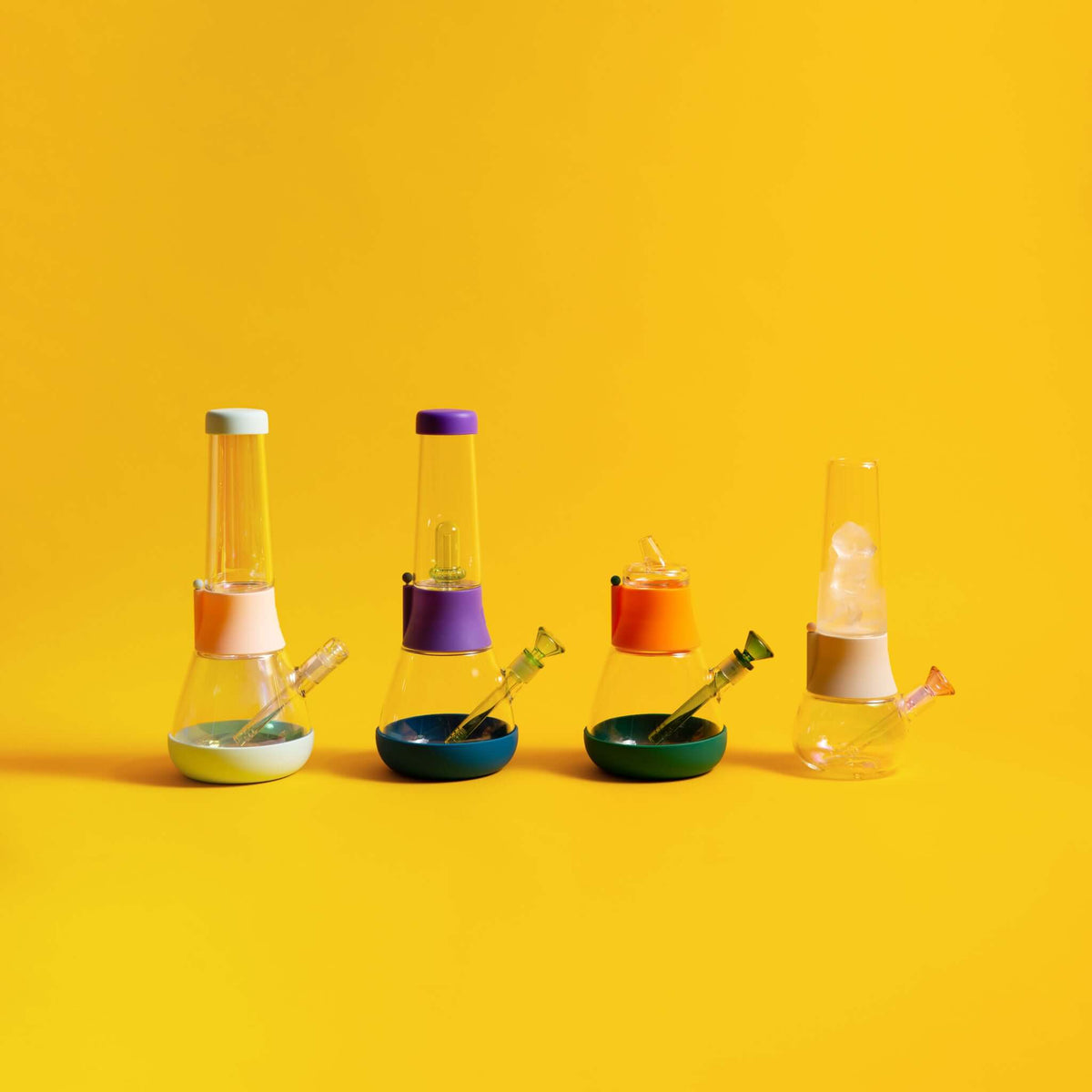 A row of custom bongs with colorful mix-and-match designs, displayed against a yellow background.