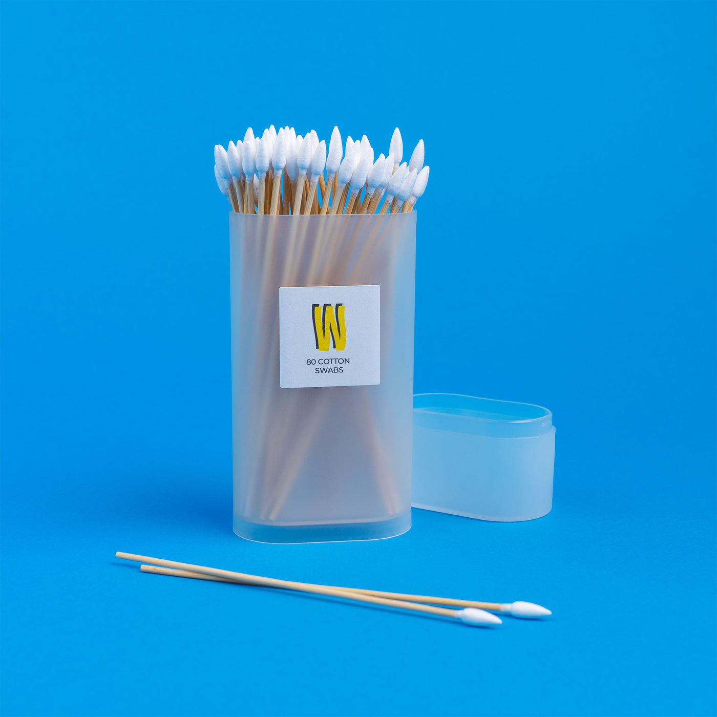 Q Tips with Package, cap half open and two Q-tips on the table, blue background 