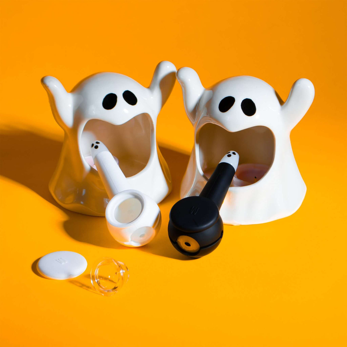 Black and white ghost pipes with clear pipe bowl, cap, and yellow backdrop