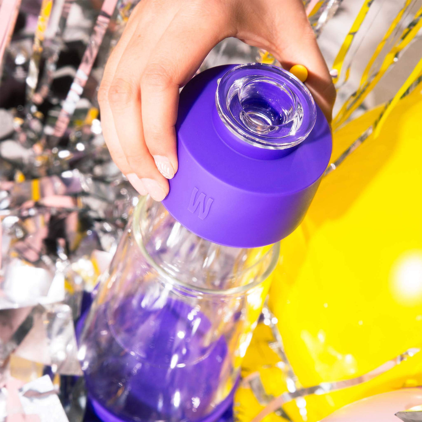 hand holding grape gravity bong with confetti 