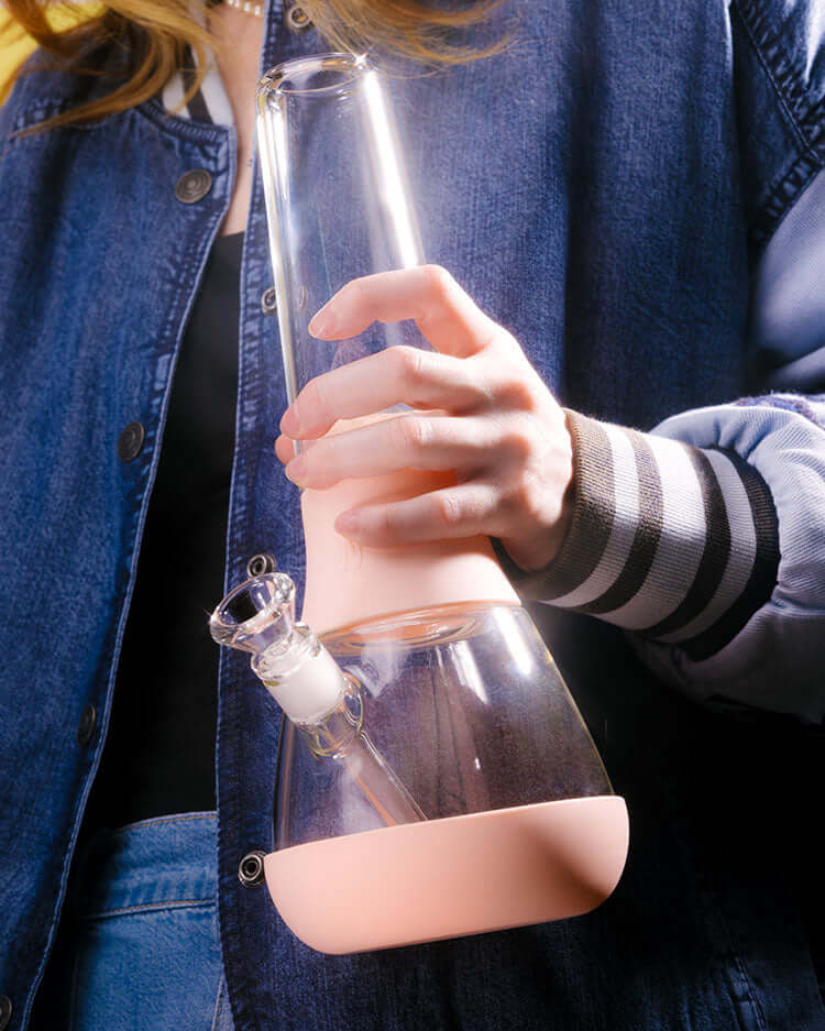 Person in denim holding Weeday designer bong in baby pink covers, showcasing its glowy, dreamy, and modern beauty.