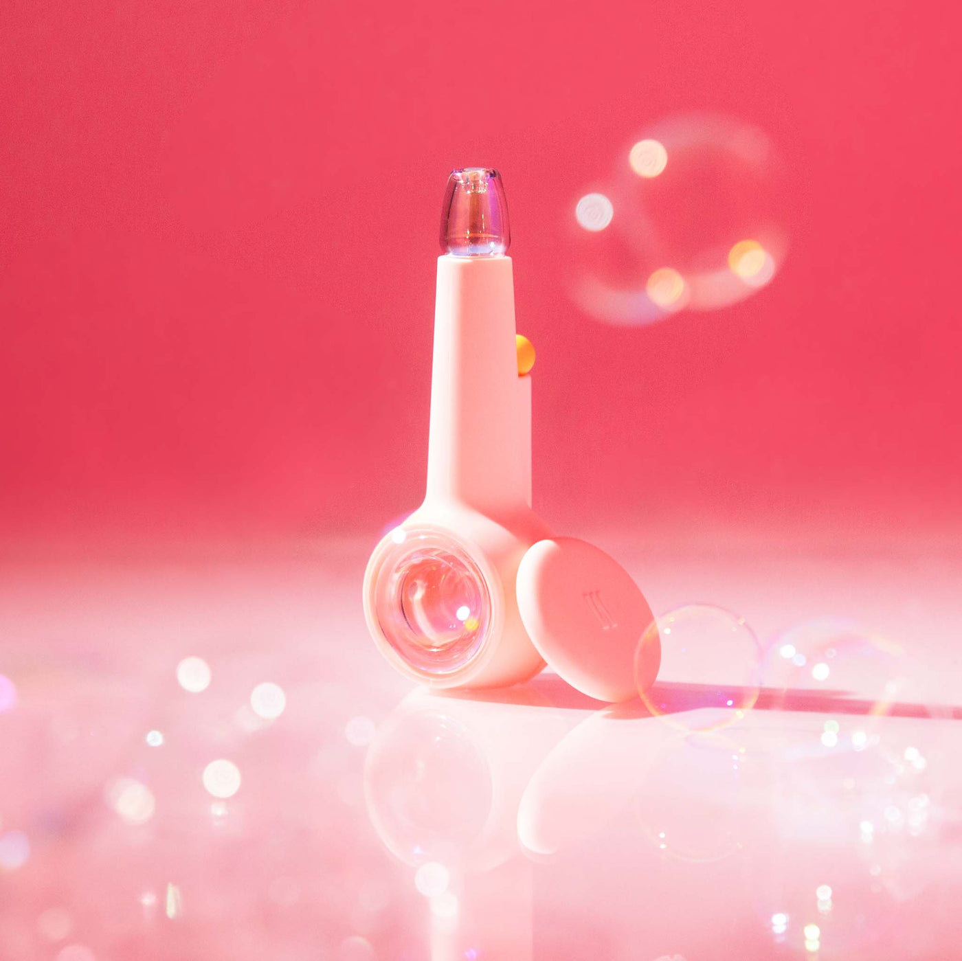 Bubblegum pink iridescent glass pipe with a silicone cover, photographed in a dreamy studio setting with soft pink hues and glowing bubble effects.