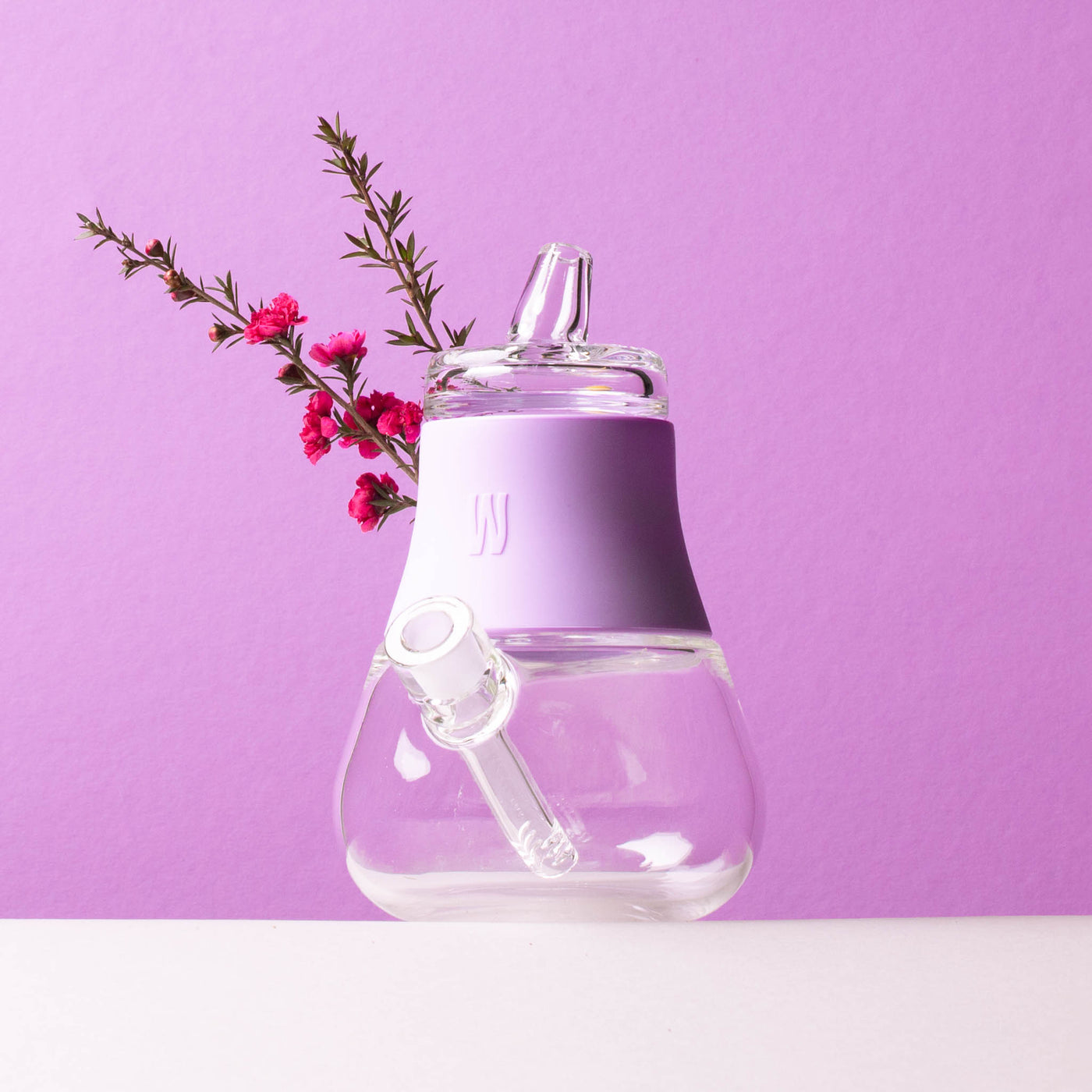 lavender bubbler with flower against lavender backdrop. 