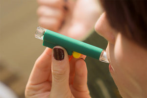 Close-up of a model using a forest green one-hitter pipe during a smoking session.