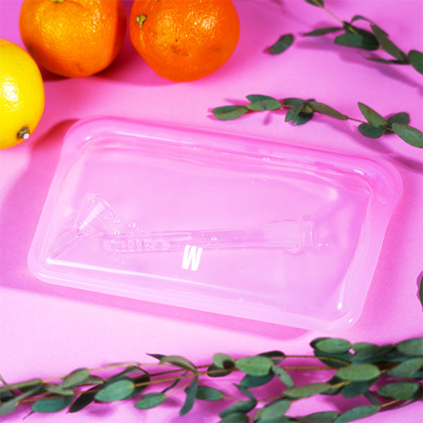 Lavender pouch with water and downstem inside, pink backdrop, orange and lemon in the back