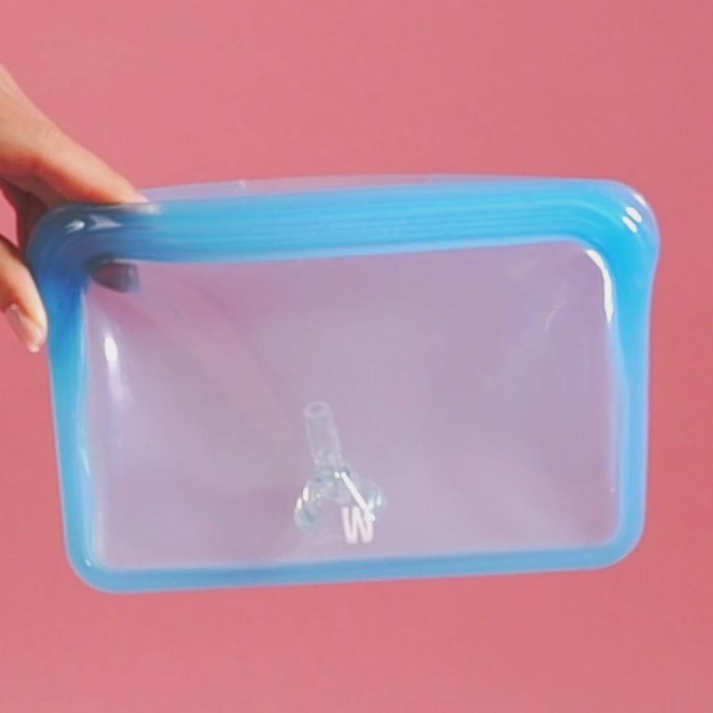 A person is using the sky cleaning pouch, pouring water in, shaking and cleaning the downstem and bowl, pink backdrop