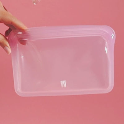 A person is using the bubblegum cleaning pouch, pouring water in, shaking and cleaning the downstem and bowl, pink backdrop