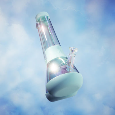 Sky blue iridescent modular bong with a protective silicone base, glimmering under natural light against a clear sky background.