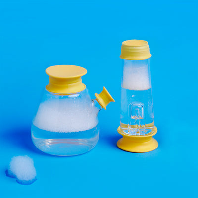 Yellow cleaning cap that is cleaning the bong base and percolator bong tube, with bubble on the table, blue background