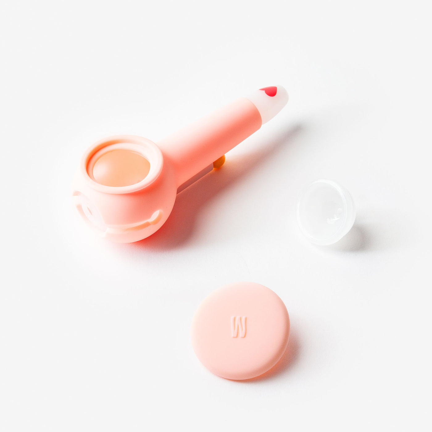 Pink smoking pipe with white base and heart design on mouth piece. 