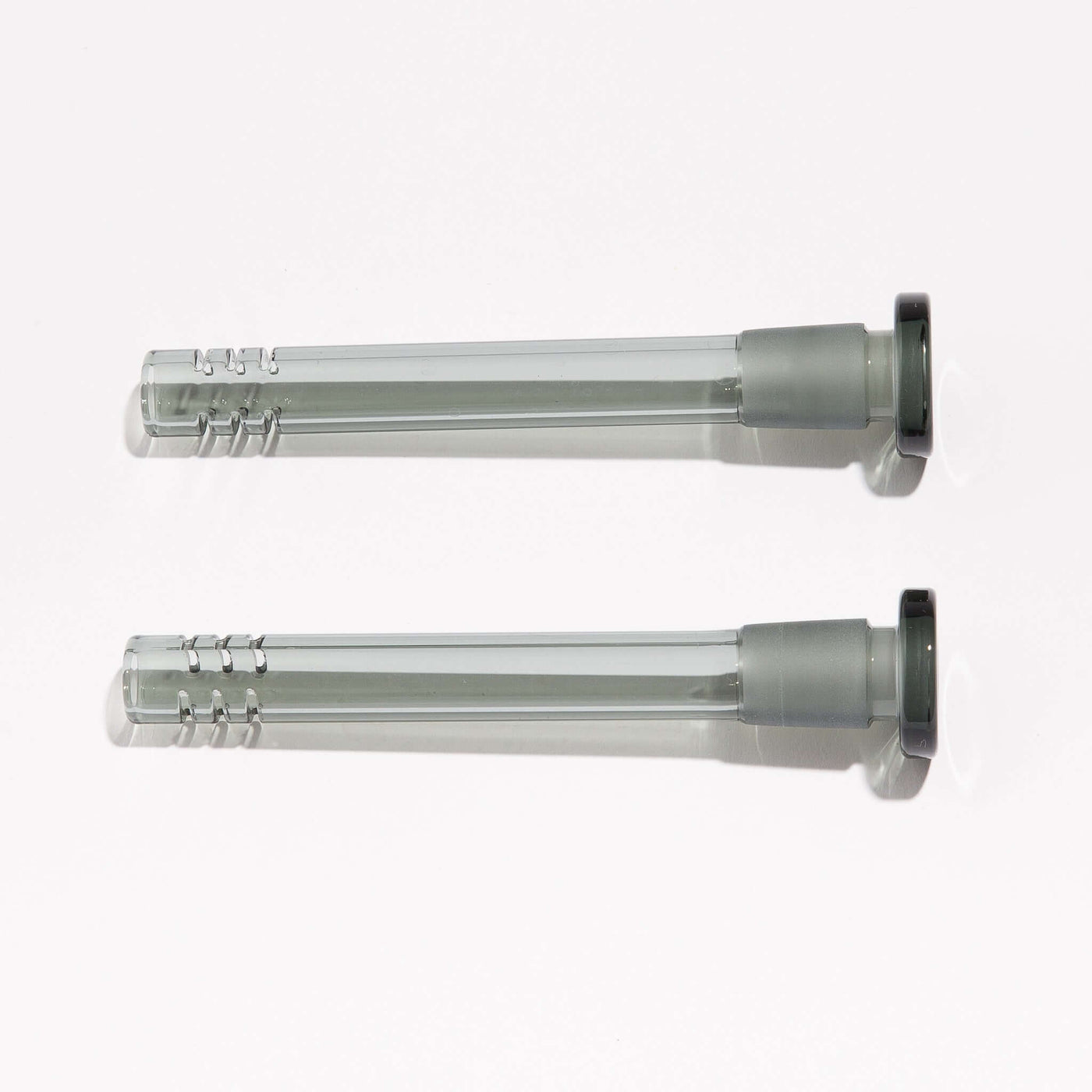 Two black borosilicate slitted downstems for enhanced filtering, sitting side by side.