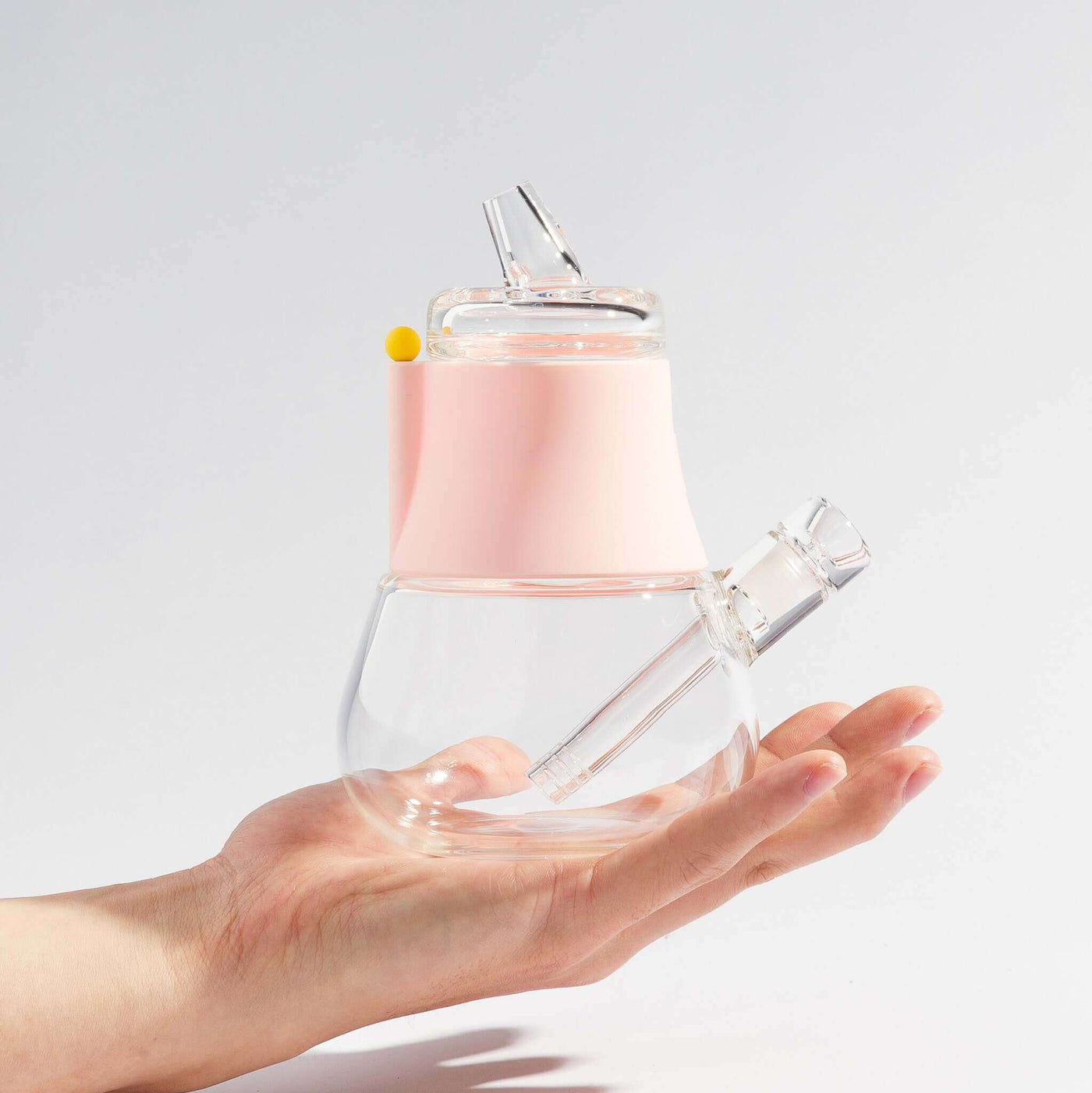 Person holding a compact-sized mini bong with bubblegum pink silicone cover on his palm.