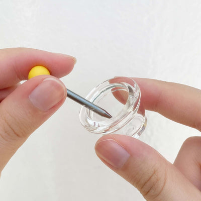 A hand is holding the glass bowl, using the poker to clean the bowl 