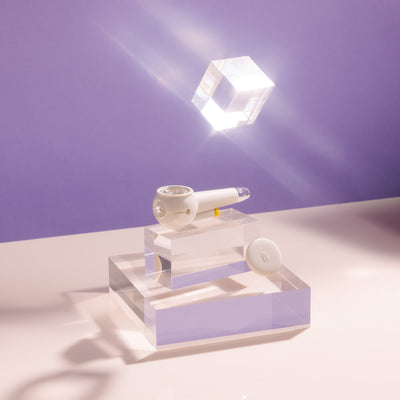 Product photo of a stylish cream white designer pipe on a block of glowing acrylic glass, cap uncovered.