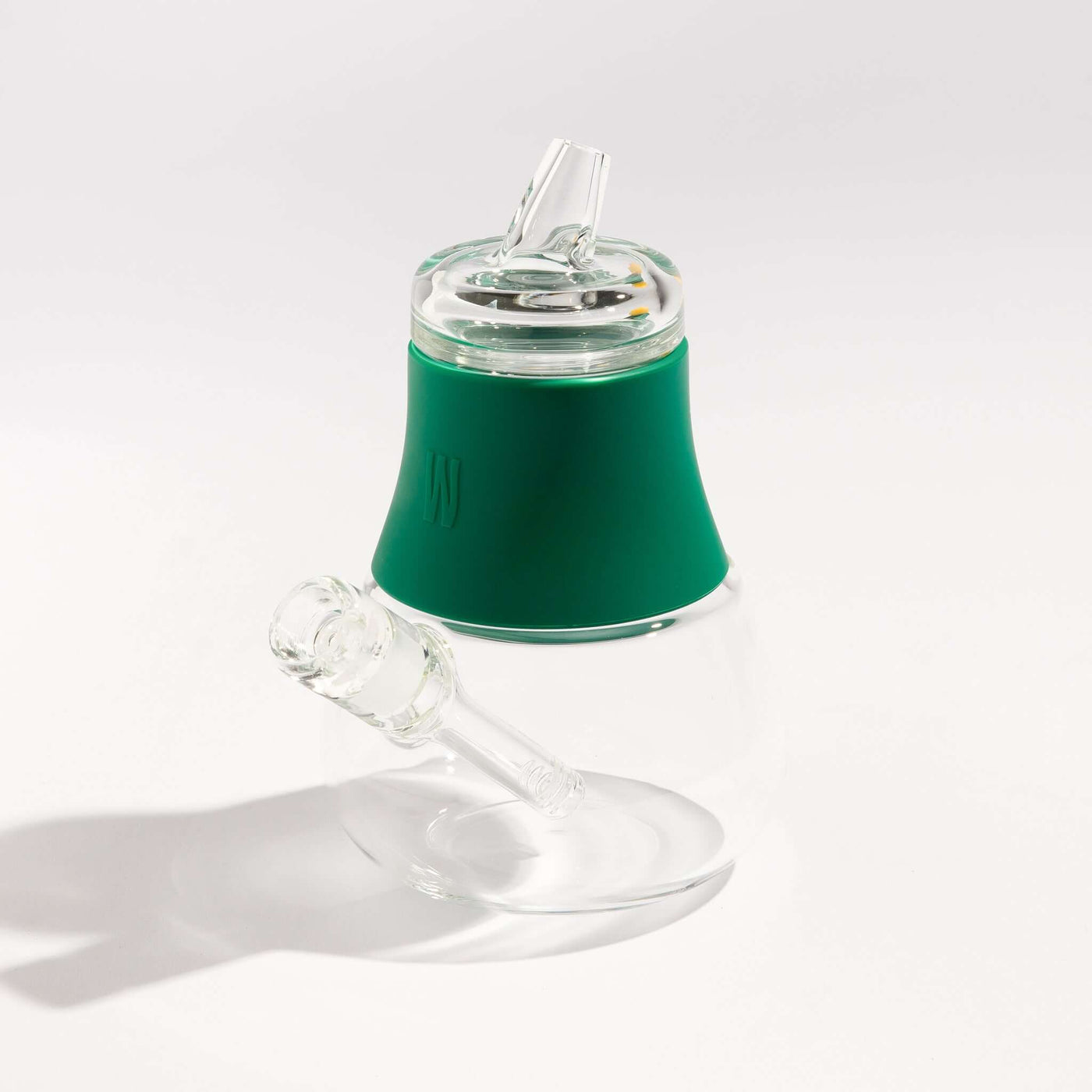 Product photo of a travel-friendly modular glass bubbler with forest green silicone accents, displayed on a table.