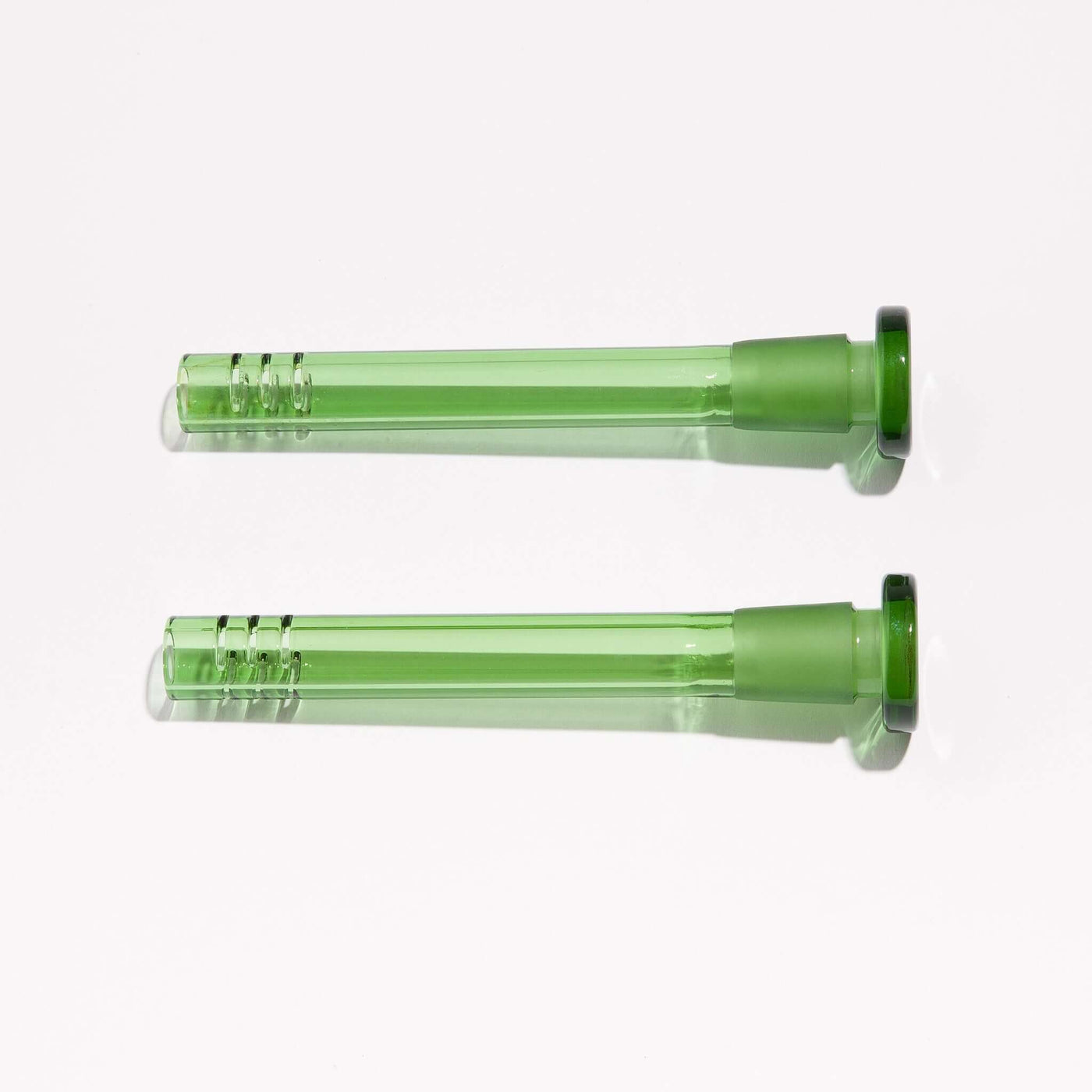 Two green borosilicate slitted downstems for enhanced filtering, sitting side by side.