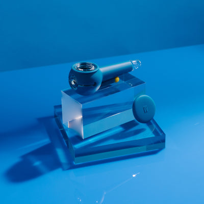 Product photo of a stylish midnight blue designer pipe on a block of glowing acrylic glass, cap uncovered.
