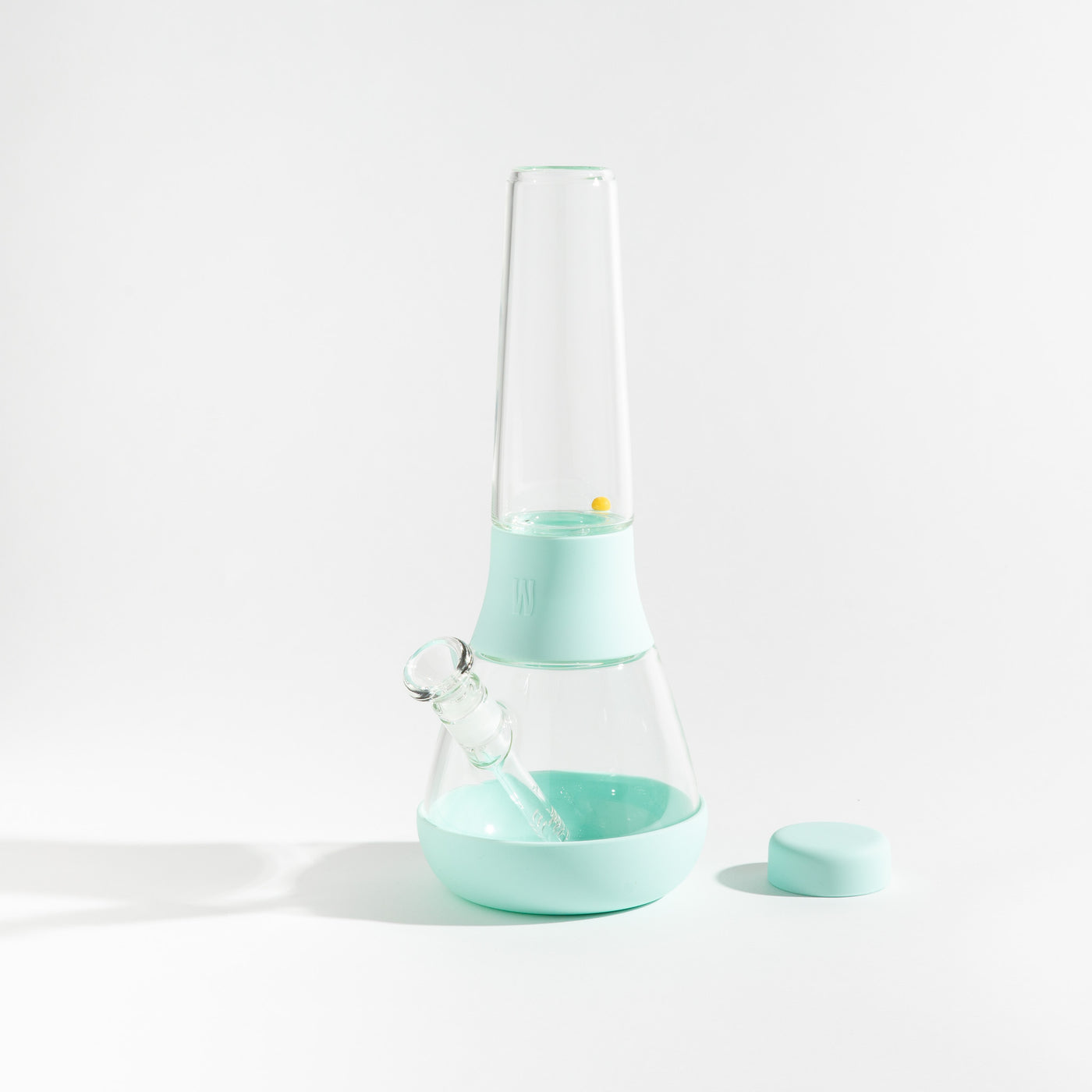 Product photo of a glass waterpipe with sky blue silicone covers, cap uncovered, placed on a table.