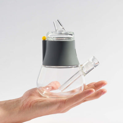 Person holding a compact-sized mini bong with smoke gray silicone cover on his palm.