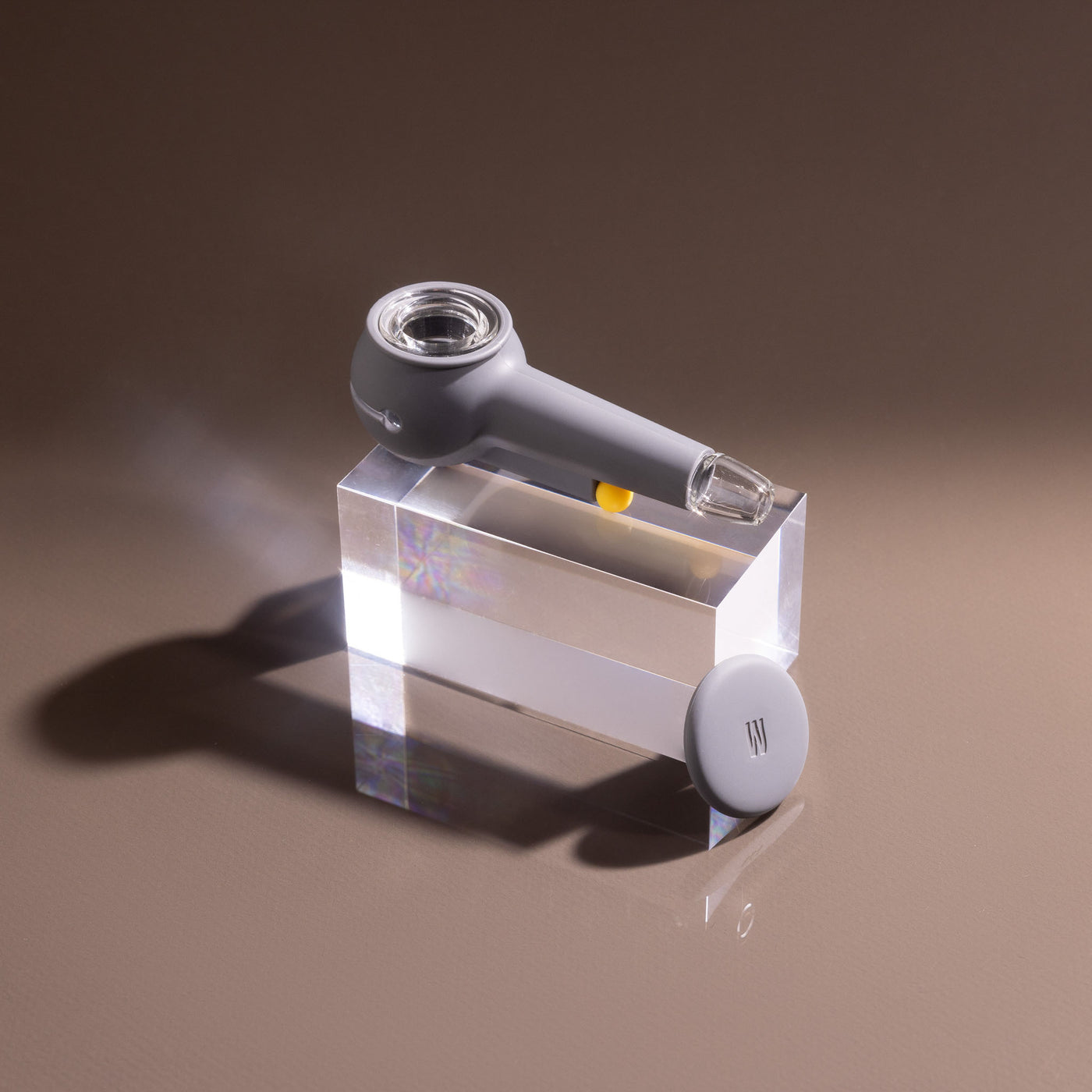 Product photo of a stylish smoke gray designer pipe on a block of glowing acrylic glass, cap uncovered.